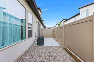 Side yard featuring a concrete patio, gravel landscaping, and tall privacy fencing