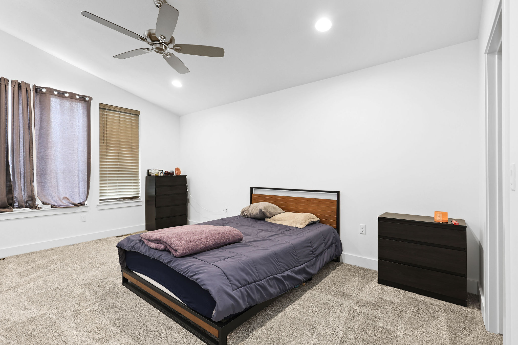 Bedroom featuring a vaulted ceiling with a ceiling fan, recessed lighting, and large windows with blinds