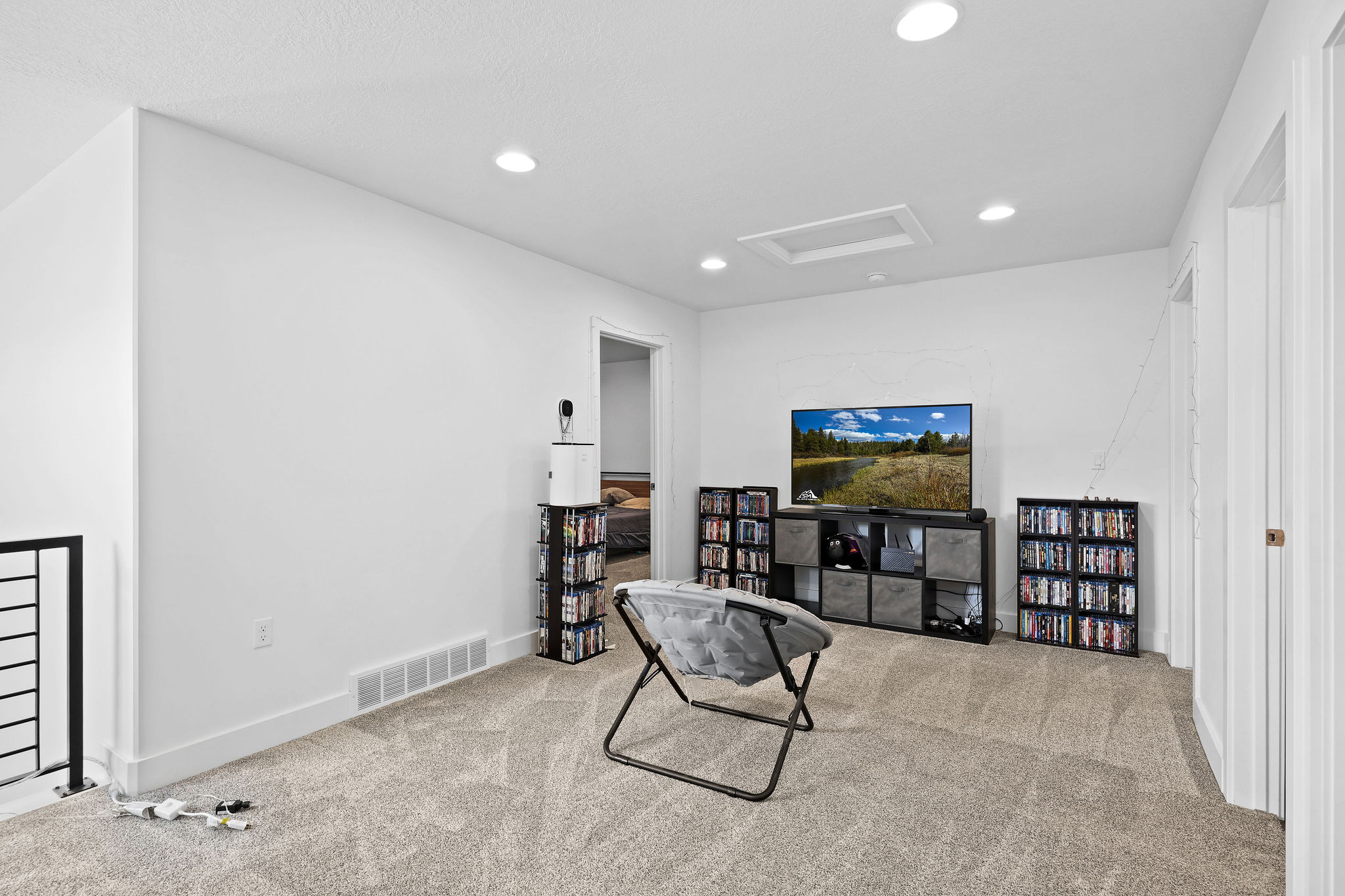 Carpeted loft area featuring recessed lighting, a white ceiling with a rectangular access panel, white baseboards, and a black metal railing