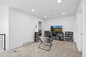 Carpeted loft area featuring recessed lighting, a white ceiling with a rectangular access panel, white baseboards, and a black metal railing