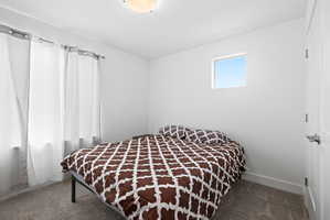 Bright bedroom featuring a flush-mount ceiling light, white walls, and soft grey carpeting