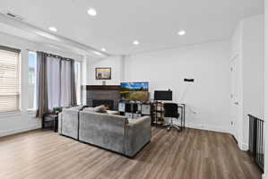 Living area featuring wood-finish flooring, recessed lighting, and white walls