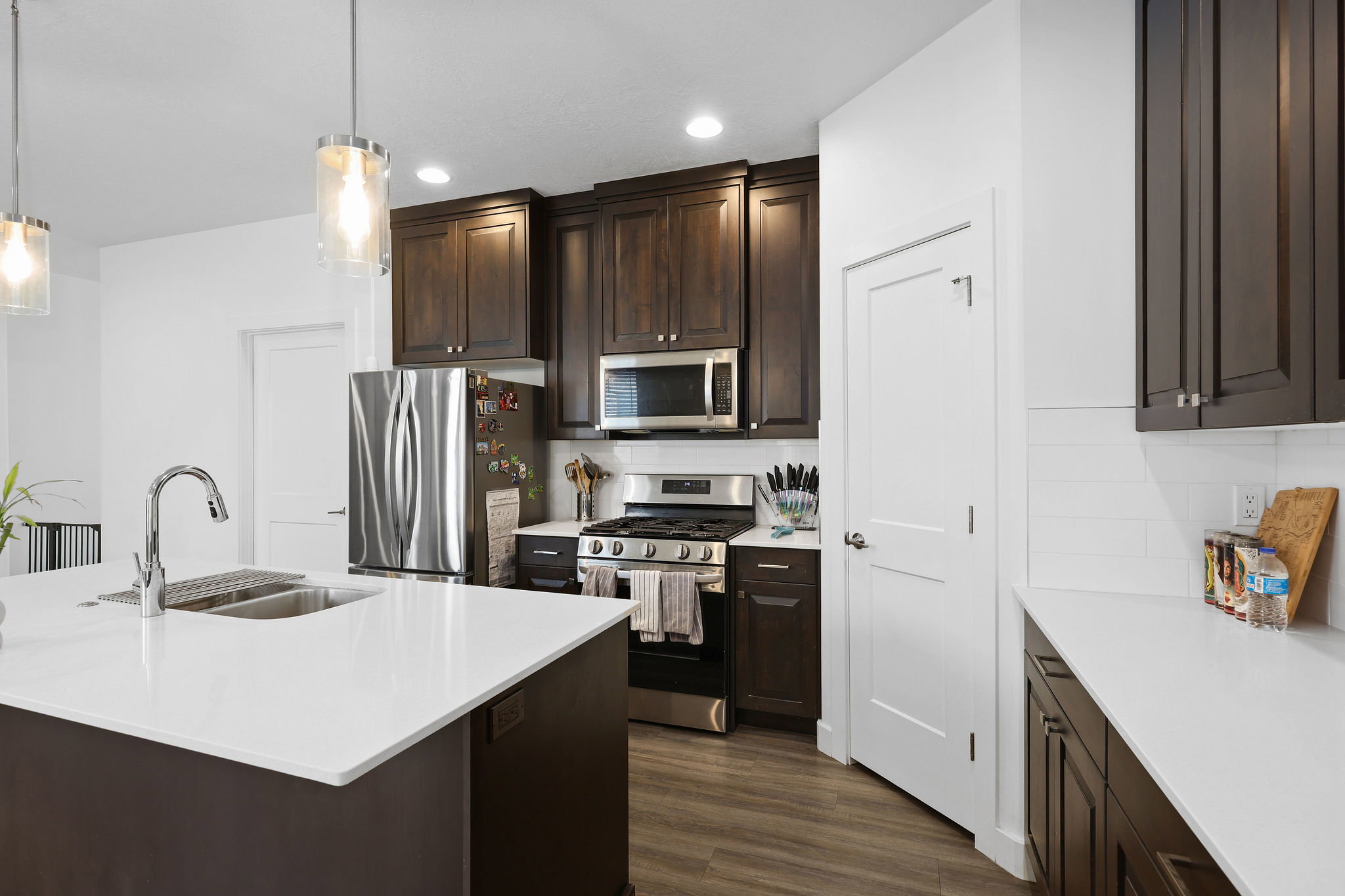 Modern kitchen featuring a large island with a stainless steel sink and gooseneck faucet