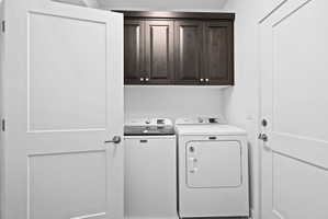 Dedicated laundry area featuring dark wood-finish cabinetry, white walls, and bright white interior doors