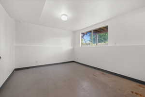 Spacious room with concrete flooring, white painted walls, and a large window