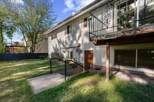 Rear exterior featuring a ground-level patio, a set of concrete stairs with metal railings, walkout basement entrance and a second-story deck with decorative metalwork