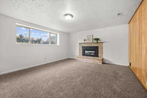 Spacious room featuring a brick fireplace with a black insert, light brown carpet, white walls, and a large horizontal window