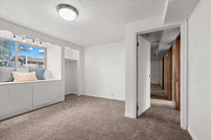 Bedroom featuring a window seat with integrated storage, track lighting, and a built-in closet with an open doorway