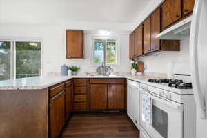 Kitchen featuring wood-finish cabinetry, light-colored countertops, a white gas range, and wood-finish flooring