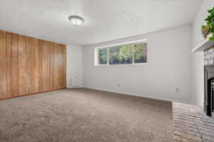 Spacious room featuring wood paneling, light gray carpeting, and a brick fireplace with a black insert