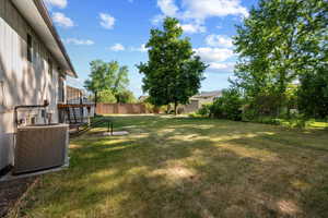 Spacious backyard featuring a substantial lawn, mature trees, and a privacy fence