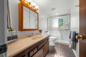 Bathroom featuring a spacious vanity with integrated sink, a wood-framed medicine cabinet, and a shower enclosure with sliding glass doors
