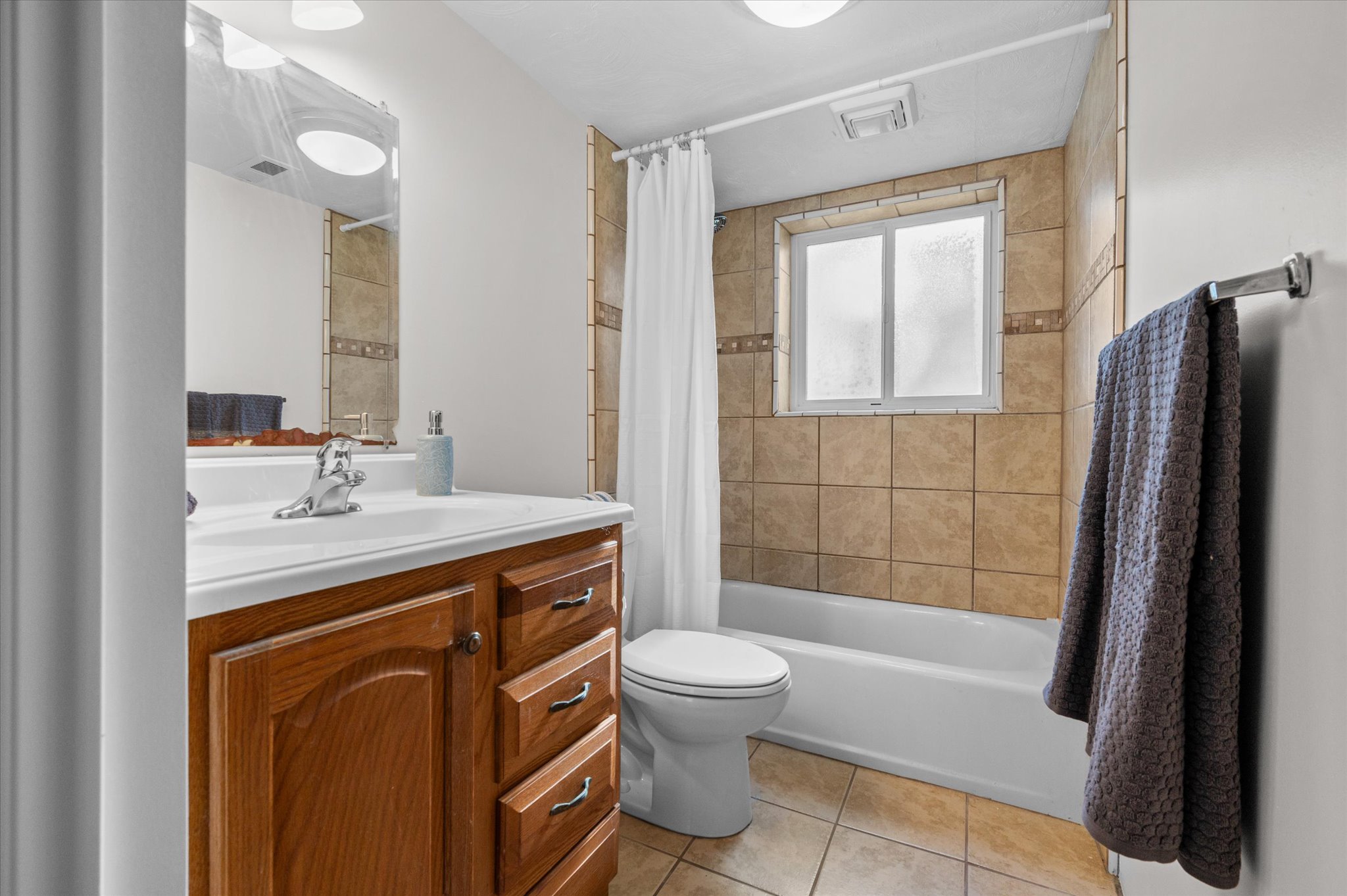 Bathroom featuring a wood-finish vanity with an integrated sink, a full-width mirror, and a toilet
