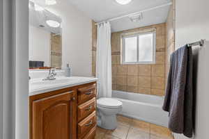 Bathroom featuring a wood-finish vanity with an integrated sink, a full-width mirror, and a toilet