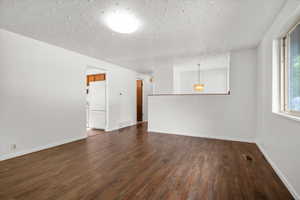 Spacious interior featuring wood-finish flooring, white painted walls, a flush-mount ceiling light, and a large window