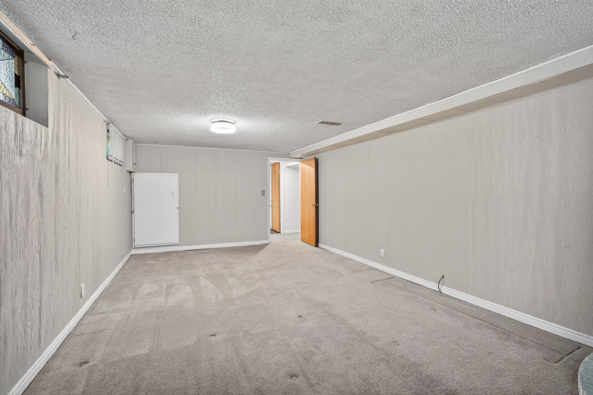Carpeted room with light gray walls, white baseboards, and a textured ceiling