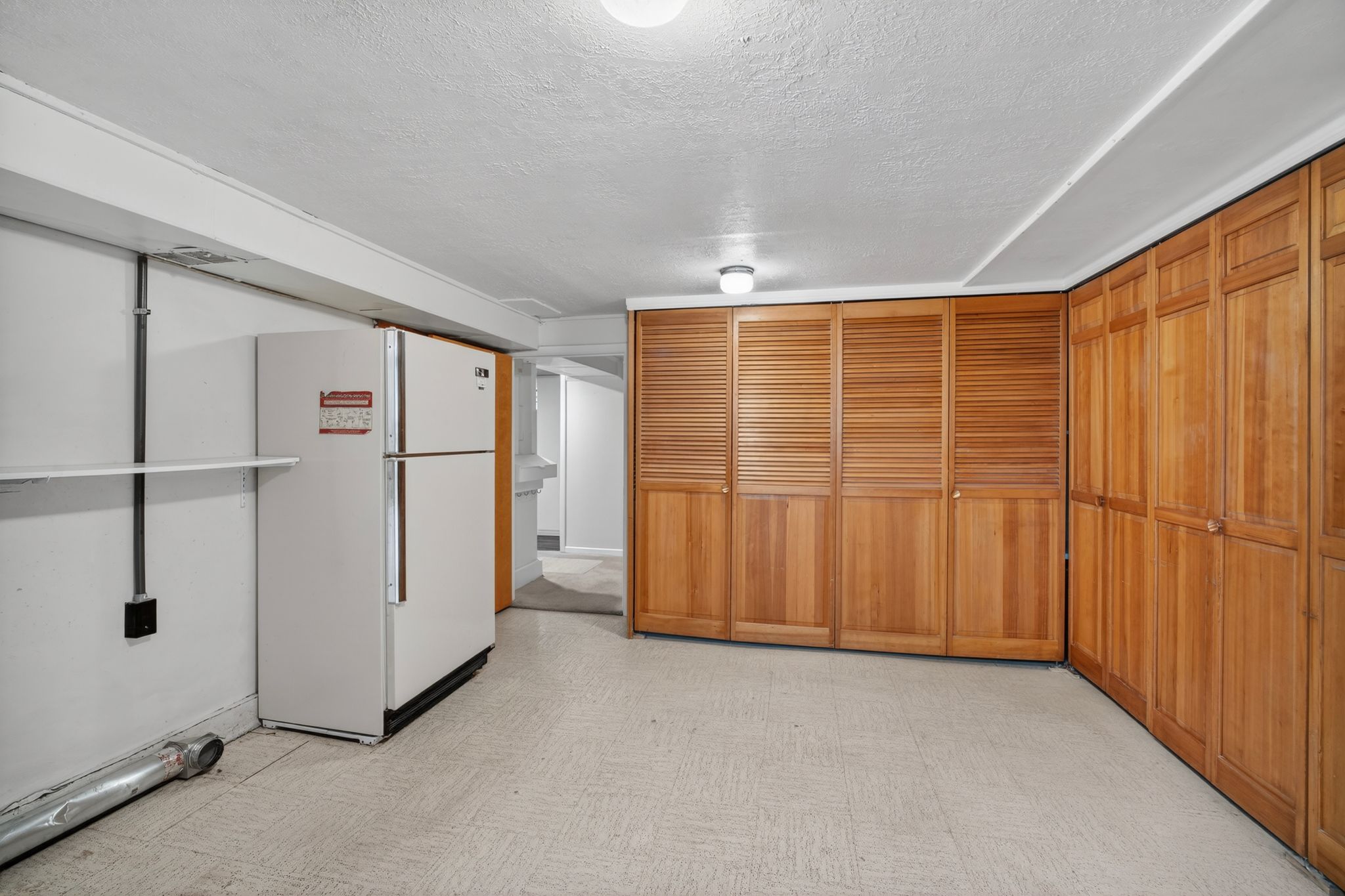 Expansive storage area featuring multiple wood bi-fold doors, white textured ceiling, and light-toned flooring