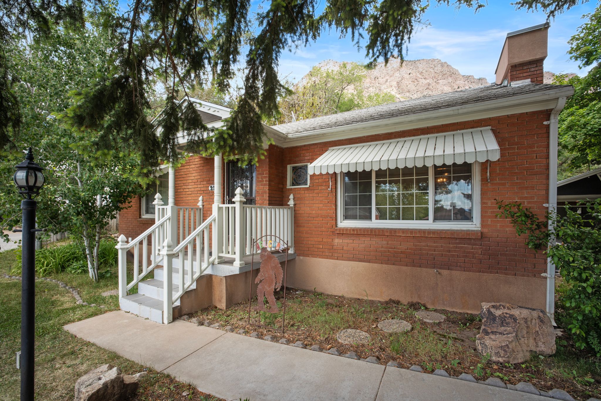 Brick exterior featuring a white aluminum awning and a front porch with white railings