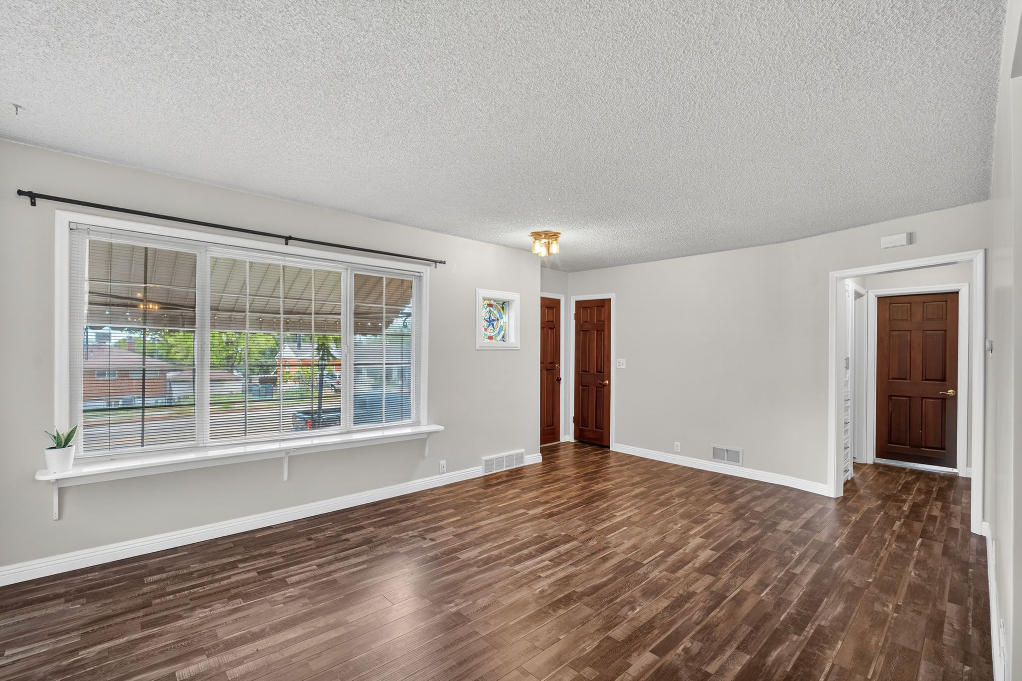 Spacious interior with dark wood-finish flooring, light gray wall paint, and white trim