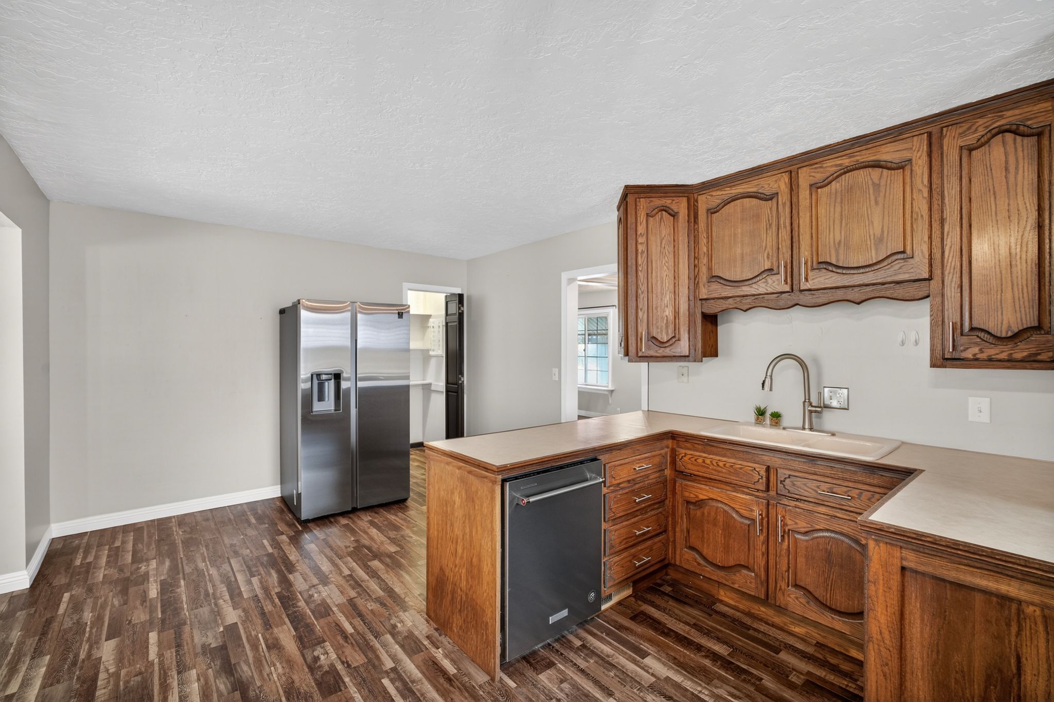 Kitchen with wood-finish flooring, light grey wall paint, and a stainless steel refrigerator