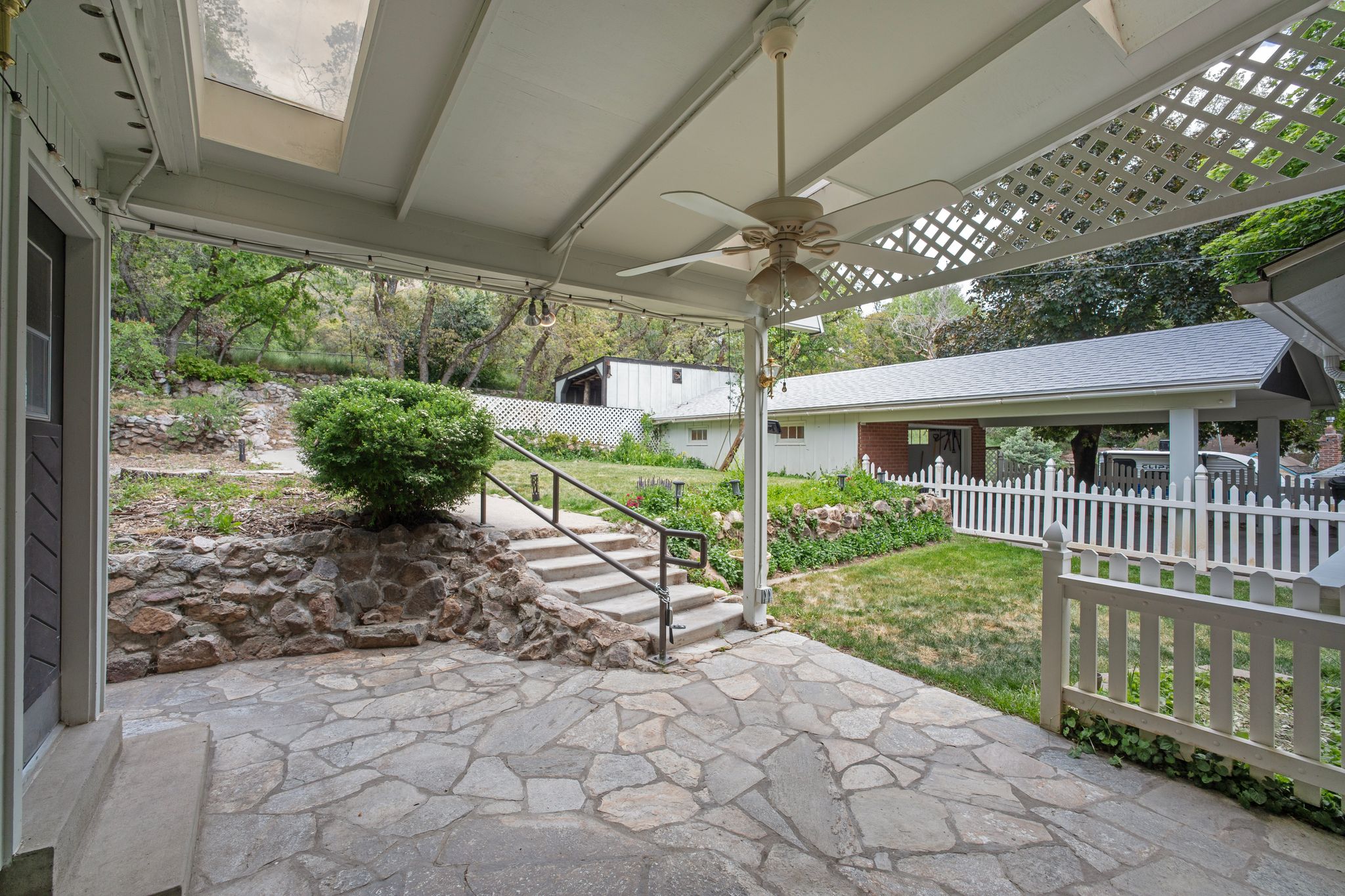 Covered patio featuring flagstone flooring, a ceiling fan, and a skylight