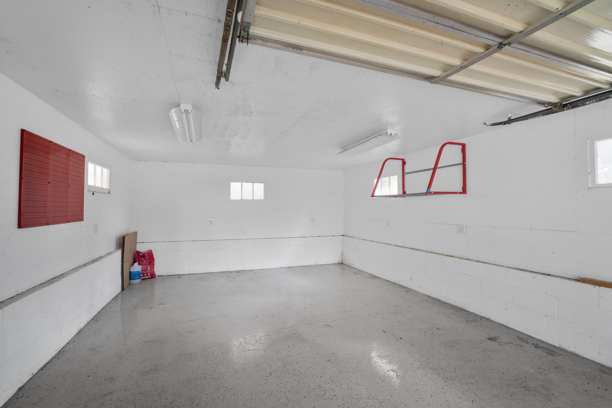 Spacious garage featuring a durable concrete floor, white painted walls, and overhead fluorescent lighting
