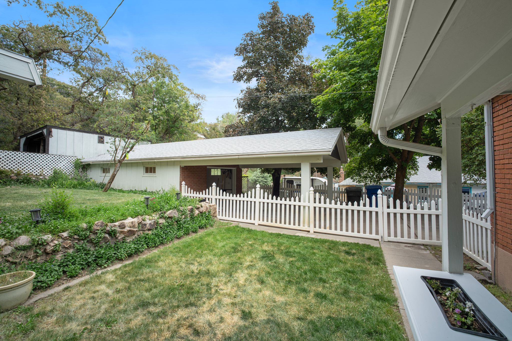 Backyard featuring a manicured lawn, a stone retaining wall, and mature trees
