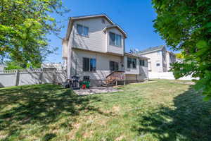 Expansive fenced backyard featuring a patio area, wood deck with stairs, and vinyl siding on the property exterior