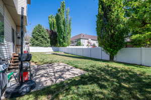 Expansive backyard featuring a concrete patio, a manicured lawn, and mature trees