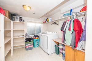 Laundry area with white appliances, built-in shelving, vinyl flooring, and a window with blinds