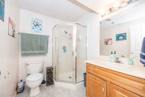 Bathroom featuring a corner shower enclosure, a single vanity with a light-toned countertop, wood cabinetry, and light-toned flooring