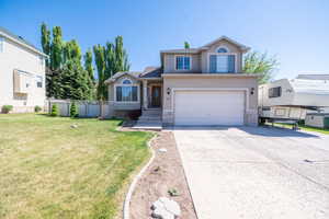 Two-story stucco residence featuring an attached two-car garage, a concrete driveway, and front landscaping