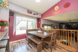 Kitchen dining nook featuring wood-finish flooring, a built-in wooden banquette, and a window providing natural light