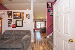 Interior entryway featuring wood-finish flooring, a white paneled door with brass hardware, and a staircase with carpeted treads