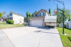 Two-story stucco exterior featuring a two-car garage, a stone veneer accent, and a paved driveway