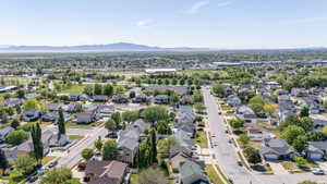 Aerial perspective showcasing a residential neighborhood with tree-lined streets, varied architectural styles, and distant mountain ranges