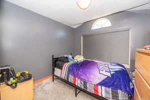 Room featuring gray wall paint, gray carpeting, and a window with a roller shade