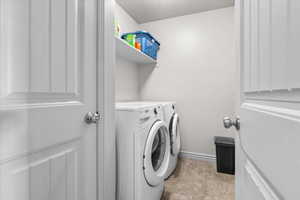 Dedicated laundry area featuring a built-in shelf, neutral wall color, and durable flooring