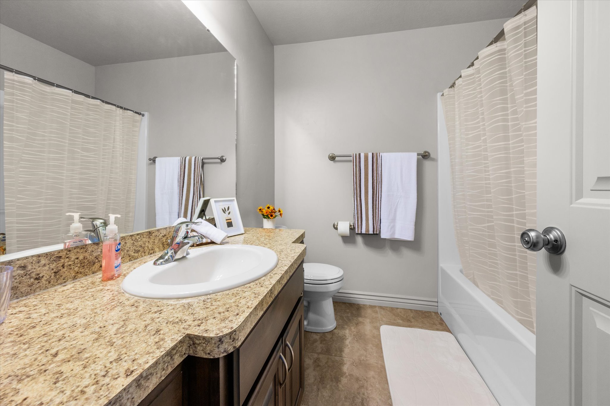 Full bathroom featuring a laminate countertop with an integrated sink, chrome faucet, and expansive wall mirror