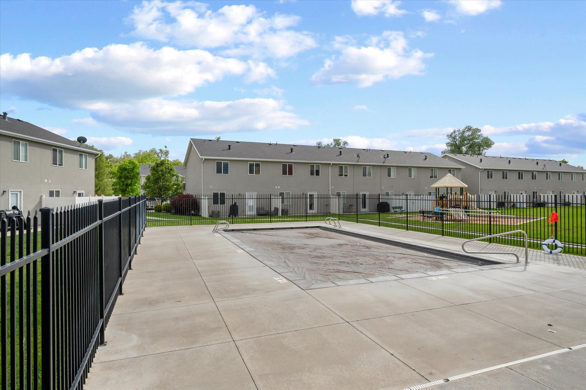 Community outdoor swimming pool with concrete surround and black metal fencing