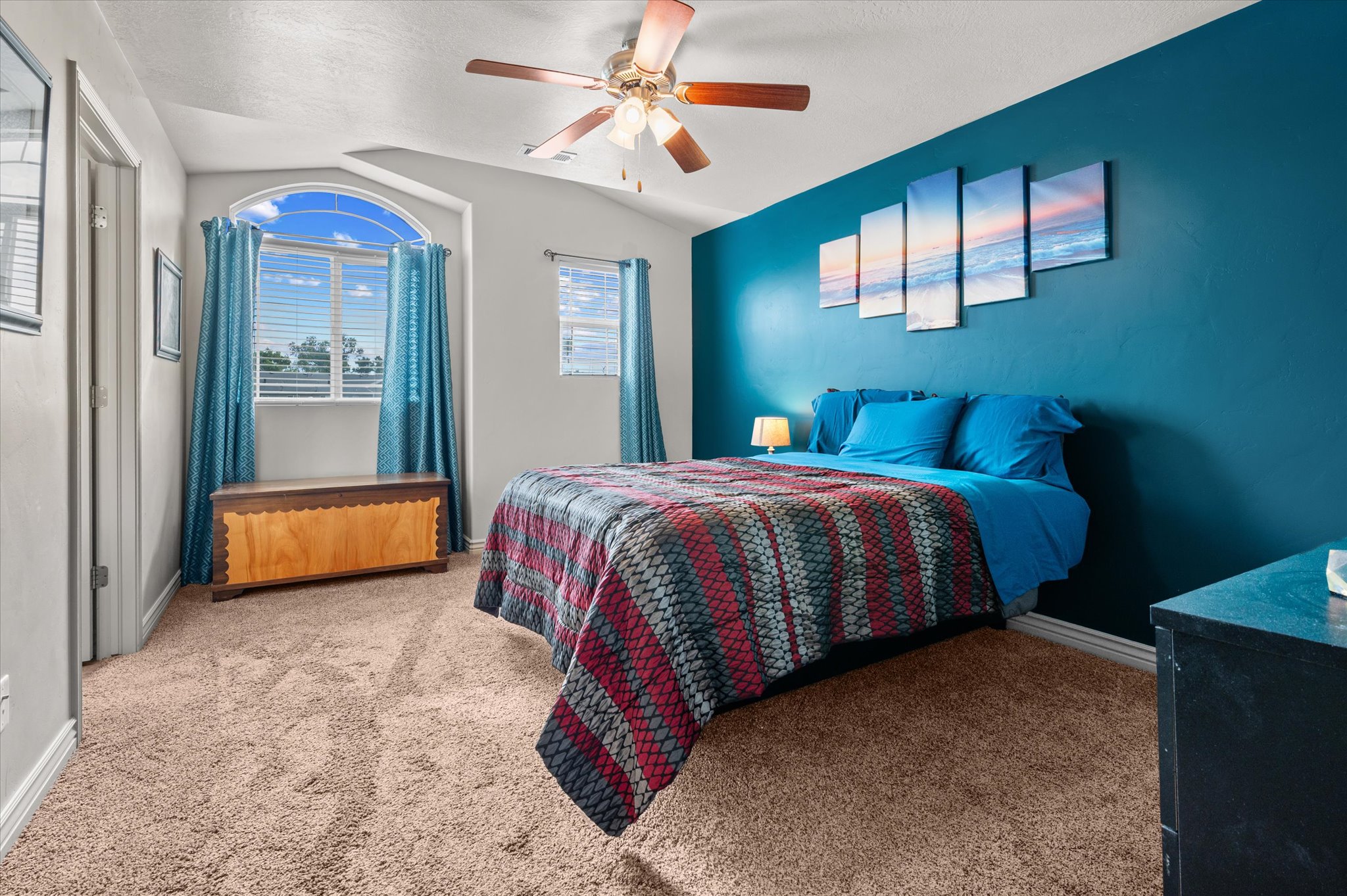 Carpeted room featuring a vaulted ceiling and an arched window