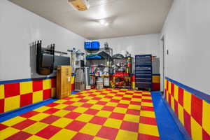 Garage interior featuring checkered red and yellow flooring, blue trim, and light walls