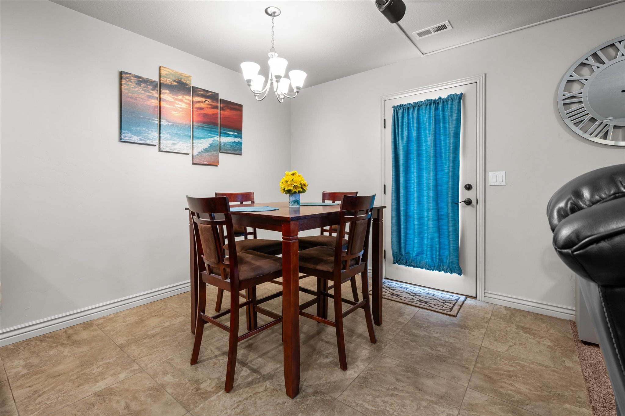 Dining area featuring tile flooring, a white exterior door, and a multi-light ceiling fixture