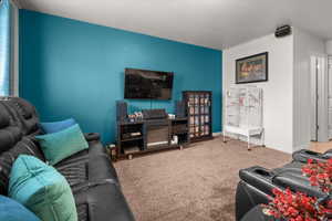 Carpeted living space with a vibrant accent wall, recessed lighting, and white baseboards
