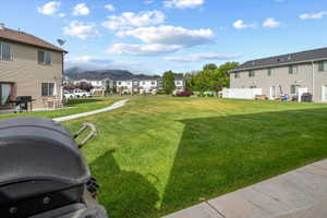 Expansive common greenspace with a concrete path, surrounded by townhomes, and featuring distant mountain scenery