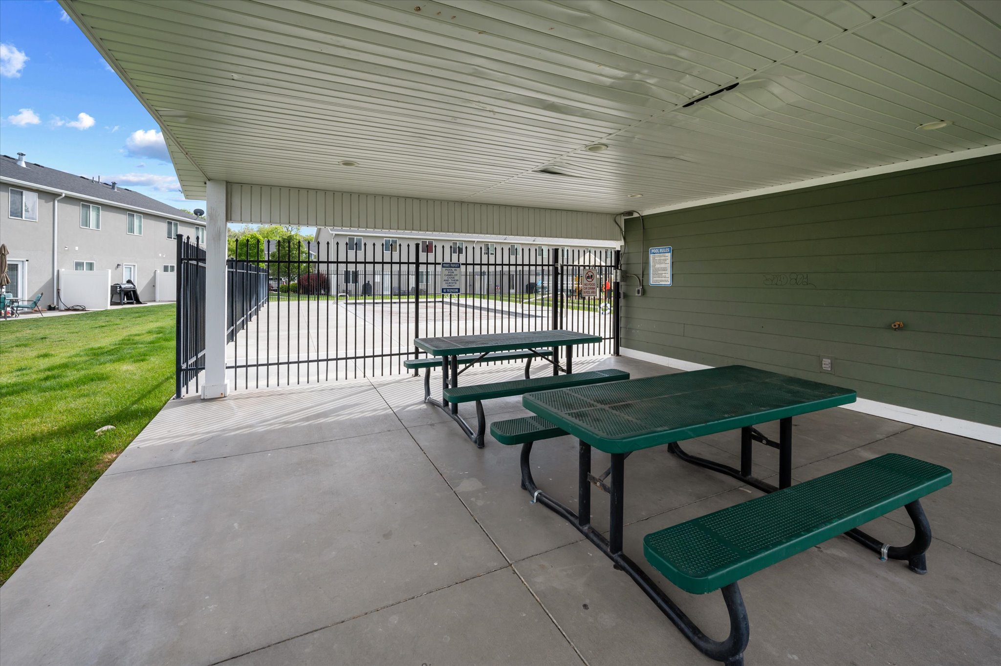 Covered patio area featuring a concrete slab and two built-in picnic tables