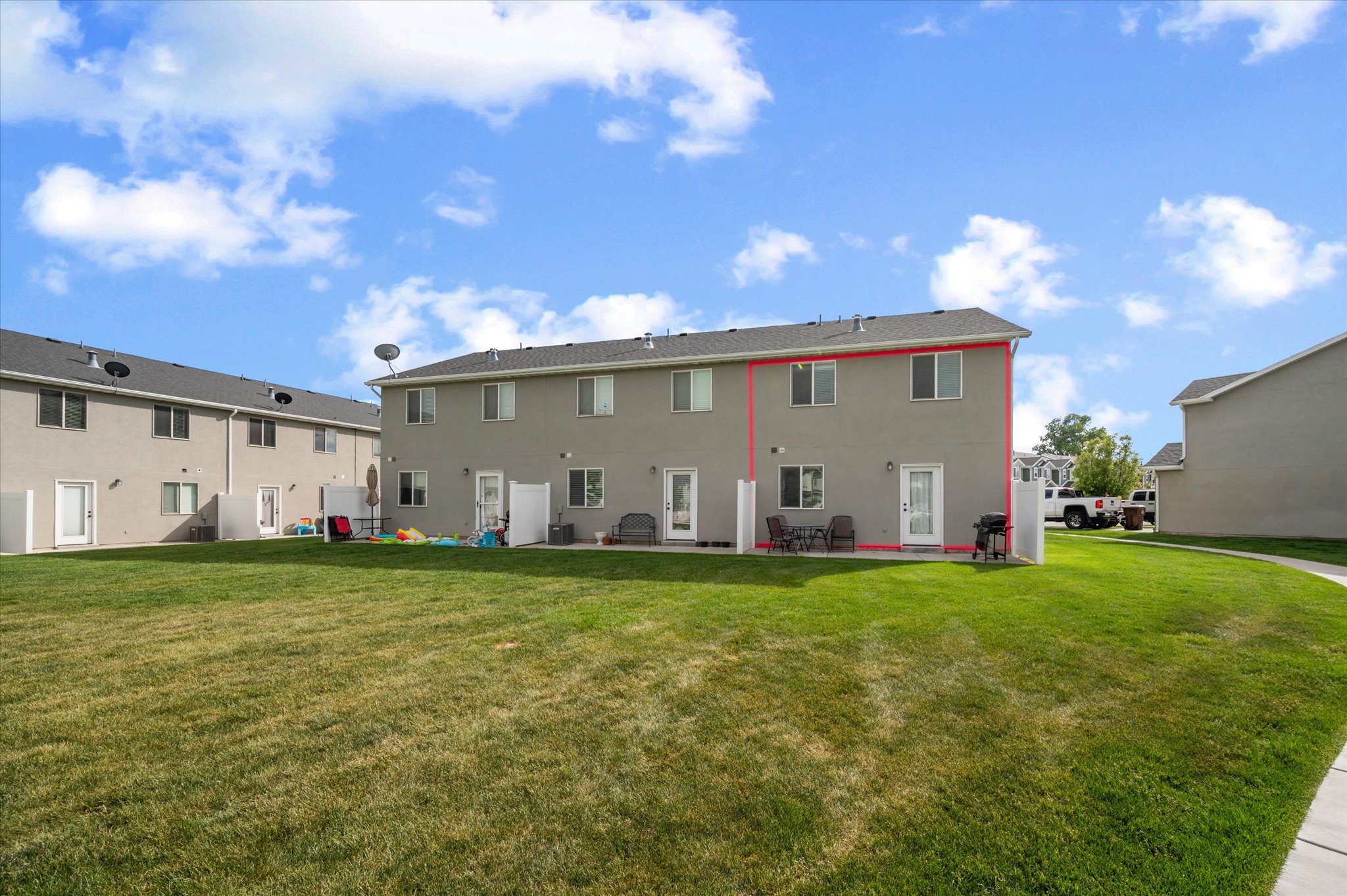 Expansive green space backing to a two-story residence with a patio door and upper-level windows