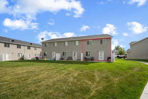 Expansive green space backing to a two-story residence with a patio door and upper-level windows