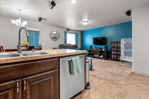 Kitchen island with a double basin sink and a high-arc faucet, rich wood cabinetry, and a built-in dishwasher