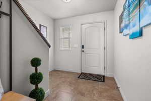 Entryway featuring tile flooring, a paneled door with an arched top light, and a single window with blinds